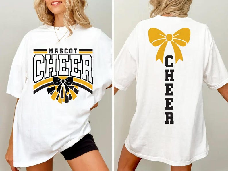 May include: White t-shirt with "MASCOT CHEER" in black, yellow, and white block letters. A black bow and yellow pom-poms are below the text. The back of the shirt has a yellow bow and the word "CHEER" in black.