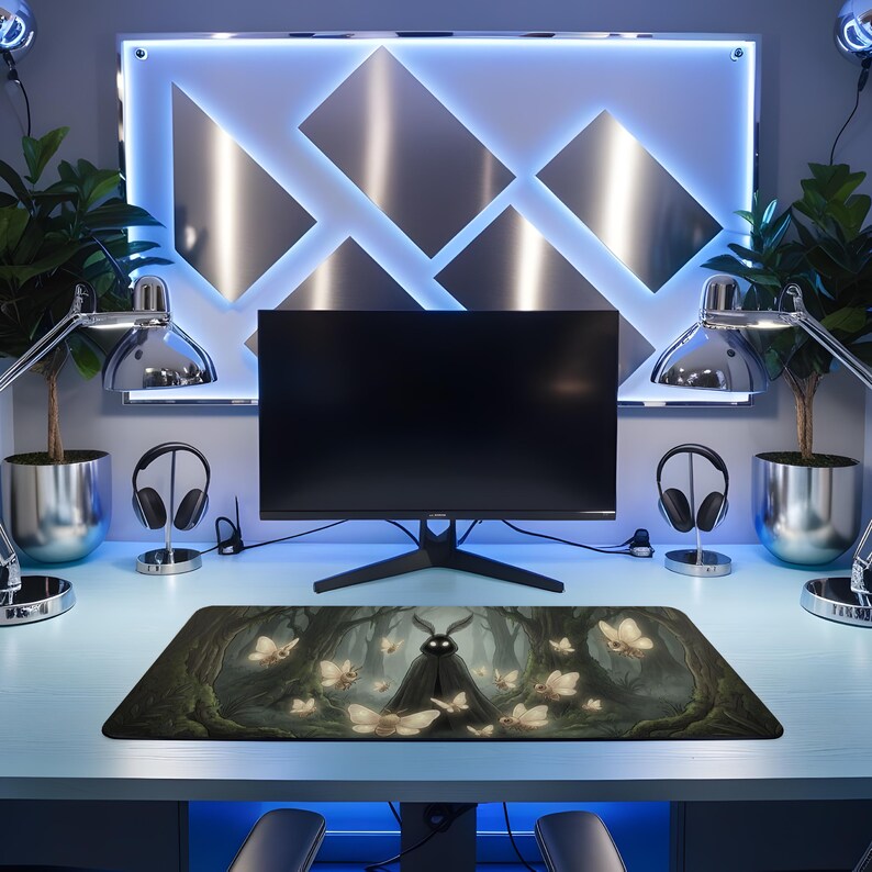 May include: A rectangular mousepad featuring a dark forest scene with glowing butterflies and a central figure. The design is predominantly green and brown, with the butterflies in shades of white and yellow. The mousepad is placed on a light blue desk, with a computer monitor and other desk accessories.