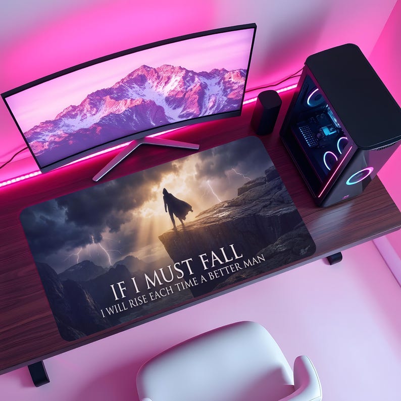 May include: A rectangular mousepad with a dramatic landscape featuring a figure on a cliff under a stormy sky. The text "IF I MUST FALL, I WILL RISE EACH TIME A BETTER MAN" is printed on the pad. The pad is on a wooden desk with a computer monitor and tower.