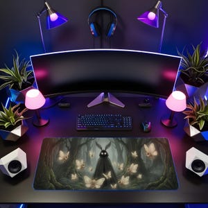 May include: A gaming setup featuring a large curved monitor, keyboard, and mouse. A custom mousepad with a forest scene and moth-like creatures is the focal point. The desk is illuminated by pink and purple lights, with speakers and plants adding to the aesthetic.