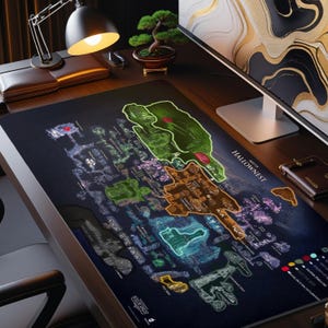 May include: A large, rectangular black desk mat featuring a detailed map of Hallownest, with green, orange, and blue highlighted areas. The text "MAP OF HALLOWNNEST" is visible. The mat is on a wooden desk with a lamp, monitor, and accessories.