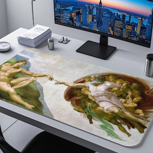 May include: A rectangular desk mat featuring a detailed reproduction of Michelangelo's "The Creation of Adam" fresco. The artwork depicts two figures with outstretched arms, set against a neutral background. The mat is placed on a white desk.