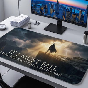 May include: A rectangular black and grey desk mat featuring a dramatic landscape with a figure on a cliff, lightning, and the text "IF I MUST FALL I WILL RISE EACH TIME A BETTER MAN."