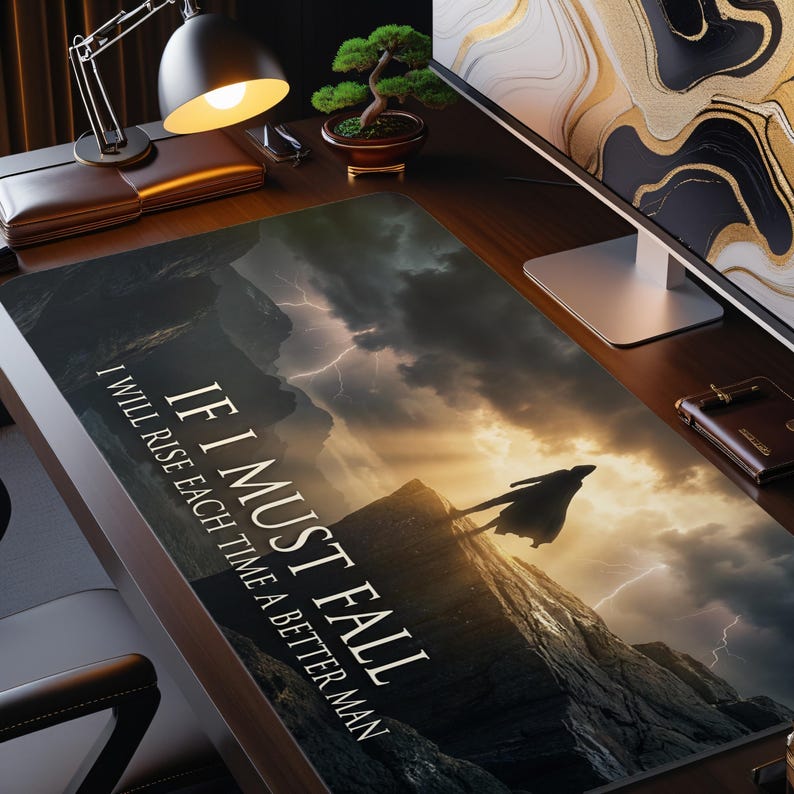 May include: A rectangular desk mat with a dramatic landscape featuring a silhouetted figure against a stormy sky and lightning. The mat has the text "IF I MUST FALL, I WILL RISE EACH TIME A BETTER MAN."