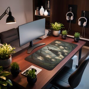 May include: A computer desk setup featuring a large monitor, a black desk lamp, and a mousepad with a forest and butterfly design. The desk is made of dark wood and has several potted plants. White headphones hang on the wall.