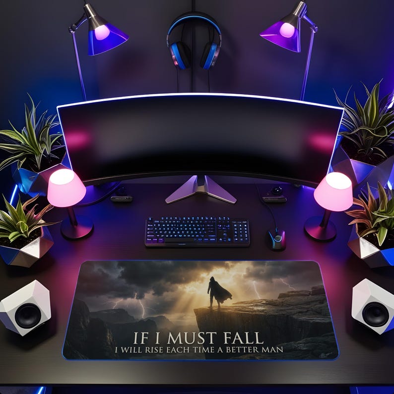 May include: A gaming setup with a curved monitor, keyboard, mouse, and mousepad. The mousepad shows a dramatic scene with a figure on a cliff and the text "IF I MUST FALL I WILL RISE EACH TIME A BETTER MAN."