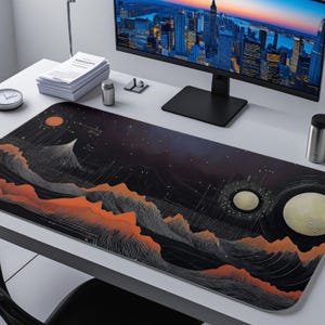 May include: A black and orange desk mat with a celestial design featuring mountains, planets, and stars. The mat has a rectangular shape and is placed on a white desk. The design is artistic and detailed, suitable for a workspace.