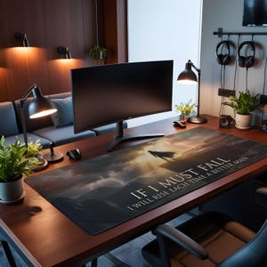 May include: A large rectangular desk mat with a dramatic landscape design, a silhouetted figure, and the text "IF I MUST FALL I WILL RISE EACH TIME A BETTER MAN." The mat is black with a sunset design.