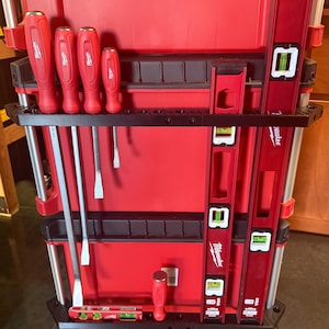 May include: A red rolling tool chest with various tools. The chest holds red screwdrivers, levels, and other tools. The tools are organized in a black holder. The chest has wheels for easy transport.