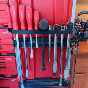 May include: A red tool organiser displaying a selection of tools, such as screwdrivers, a hammer, sockets, and wrenches. The tools are neatly arranged in a black holder, with red handles and silver shafts. The organiser is part of a larger red tool storage system.