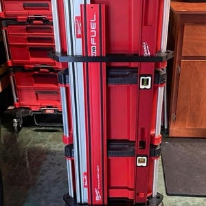Puede incluir: Sistema de almacenamiento de herramientas Milwaukee rojo y negro con base rodante. El sistema incluye múltiples cajas de herramientas apiladas y un nivel. El nivel es rojo con un indicador de burbuja. Diseñado para uso intensivo.