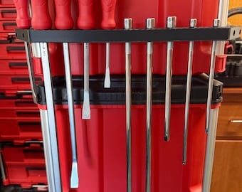 May include: A red tool organizer with a variety of tools. The organizer has a black metal rack holding screwdrivers and other tools. The screwdrivers have red handles. The tools are arranged vertically, showcasing a range of sizes and types.