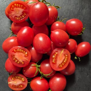 Op de afbeelding: Een verzameling felrode cherrytomaatjes, sommige heel en sommige doormidden gesneden om de zaden en het vruchtvlees binnenin te onthullen. De tomaten zijn in een groep gerangschikt en het woord Shimofuri staat in witte tekst rechtsonder.