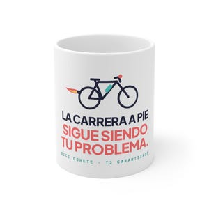 May include: A white ceramic mug featuring a dark blue bicycle graphic with a flame exhaust, accompanied by the text LA CARRERA A PIE SIGUE SIENDO TU PROBLEMA and the smaller text BICI COHETE T2 GARANTIZADO in blue and red.