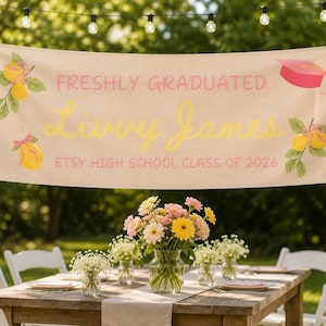 Może przedstawiać: Baner z napisem "Freshly Graduated Livvy James Etsy High School Class of 2026" jest wyświetlany na zewnątrz. Baner jest ozdobiony ilustracjami cytryn i czapką absolwenta. Stół jest nakryty kwiatami i białymi krzesłami.