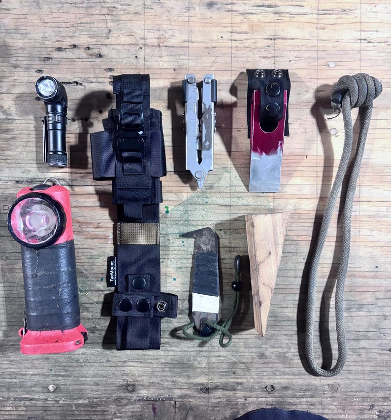 May include: A collection of outdoor gear including a black flashlight, a red and black headlamp, a black TacMount sheath, a silver multi-tool, a red and silver tool in a black holder, a small knife, a wooden wedge, and a long gray rope with a knot.