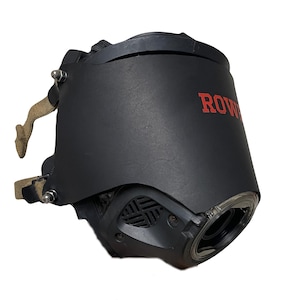 May include: A black protective face mask featuring a smooth matte finish and the red text ROWE printed on the side. The mask includes a clear circular lens, a side ventilation grille, and beige fabric straps secured with silver metal hardware bolts.