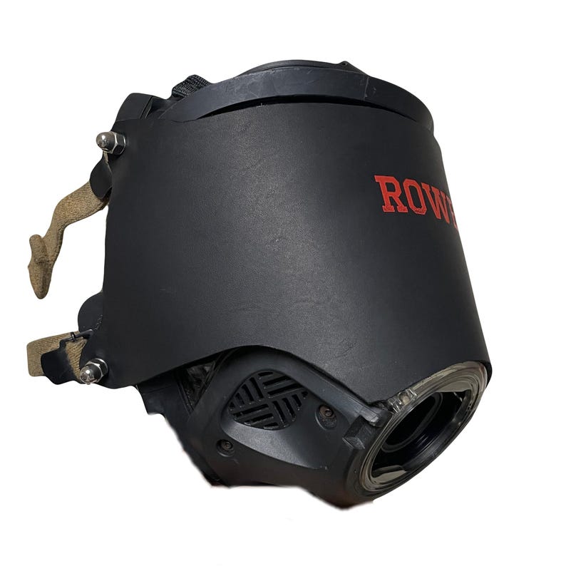 May include: A black protective face mask featuring a smooth matte finish and the red text ROWE printed on the side. The mask includes a clear circular lens, a side ventilation grille, and beige fabric straps secured with silver metal hardware bolts.