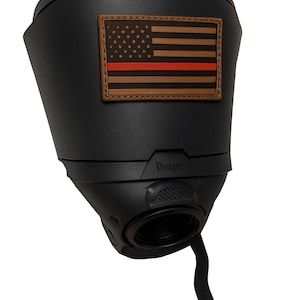 May include: A matte black tactical-style cover featuring a rectangular brown leather patch with a debossed American flag design and a horizontal red stripe. The word Disigen is embossed on the lower section, which includes a circular opening and a strap.