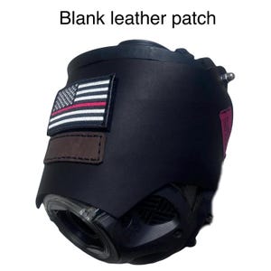 May include: A black protective helmet cover featuring a rectangular American flag patch with a thin red line, a blank brown leather patch, and a small red side tag. The text "Blank leather patch" is displayed above the helmet cover.