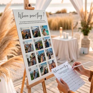 May include: A wooden easel displaying a white sign with the text "Where were they?" and twelve small photos. The sign is part of a wedding game. A person is holding a matching game sheet.