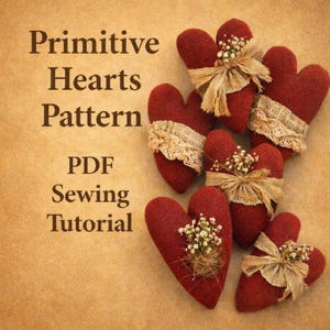 Può includere: Cuori di stoffa rossa fatti a mano, adornati con pizzo, fiori secchi e fiocchi di nastro. L'immagine include il testo "Primitive Hearts Pattern PDF Sewing Tutorial" in un font in stile vintage, che suggerisce un progetto di cucito.