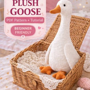 May include: A plush white goose with an orange beak and feet sits in a wicker basket lined with lace. The image includes text that reads "3 Sizes", "Plush Goose", "PDF Pattern + Tutorial", and "Beginner Friendly".