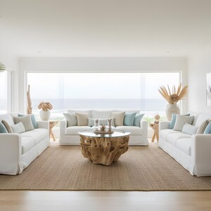 May include: A spacious living room featuring three white sofas with light blue and beige cushions. A unique wooden coffee table sits on a woven rug. Decorative vases and side tables add to the coastal theme, creating a bright and airy space.