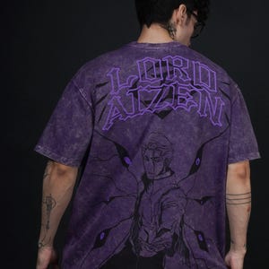 May include: Purple t-shirt with a graphic design. The back features the text "LORD AIZEN" and the front has a character illustration. The shirt has a vintage wash effect, giving it a worn appearance.
