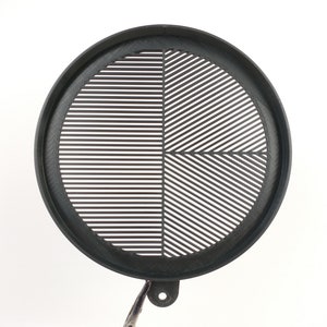 May include: A black round speaker grille with a geometric pattern of horizontal and diagonal lines.