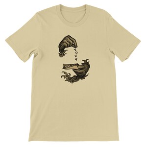 Könnte beinhalten: Ein beiges T-Shirt mit kurzen Ärmeln und einer schwarzen grafischen Illustration von zwei Händen, die ein kleines Stück Papier mit dem Text "YOUR OPINION" halten, umgeben von stilisierten, wirbelnden rauch- oder flammenartigen Elementen.