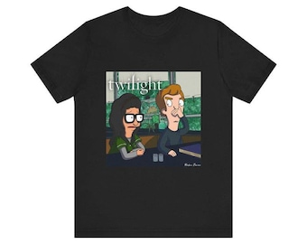 May include: A black t-shirt featuring a graphic print of two cartoon characters sitting at a table. The character on the left has dark hair and glasses, while the character on the right has light brown hair. The word twilight is printed above them.