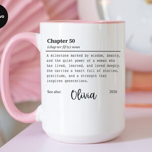 May include: White ceramic mug with a pink handle and rim. The mug features the text "Chapter 50" with a definition, the name "Olivia", and the year "2026". The mug is a gift for a milestone birthday.