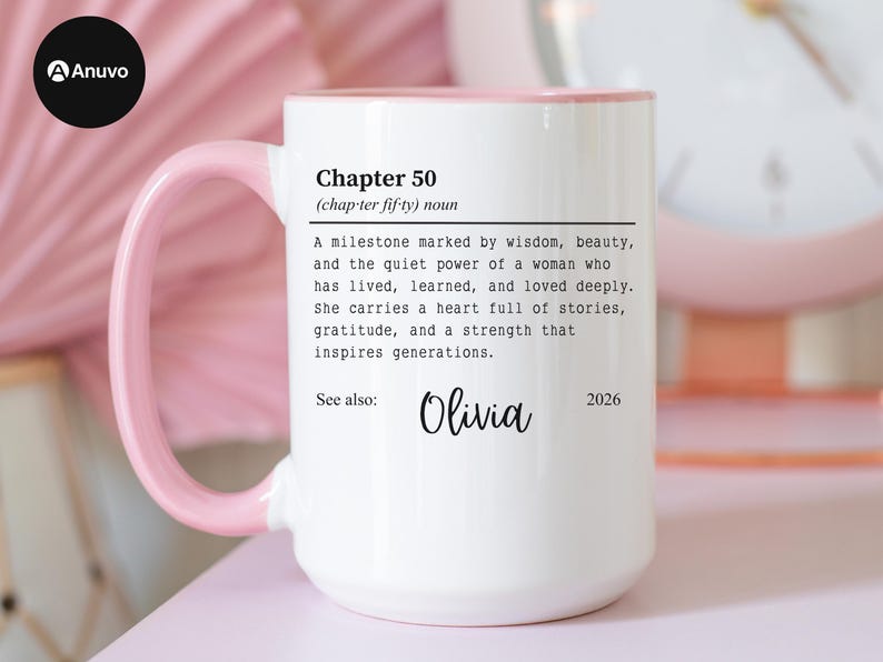 May include: White ceramic mug with a pink handle and rim. The mug features the text "Chapter 50" with a definition, the name "Olivia", and the year "2026". The mug is a gift for a milestone birthday.