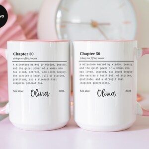 May include: Two white ceramic mugs with pink handles and rims. Each mug features the text "Chapter 50" with a definition and the name "Olivia" below. A clock is visible in the background.