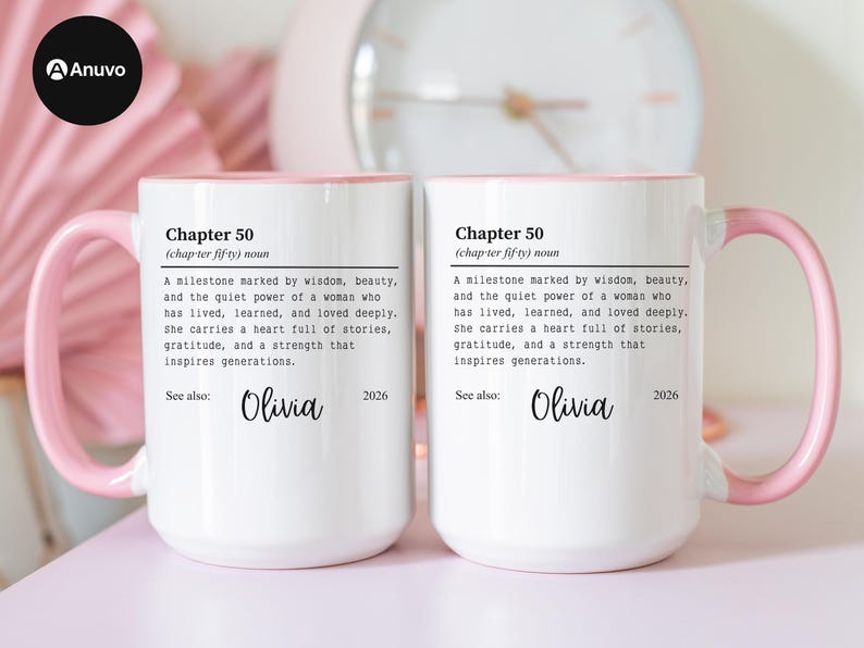 May include: Two white ceramic mugs with pink handles and rims. Each mug features the text "Chapter 50" with a definition and the name "Olivia" below. A clock is visible in the background.
