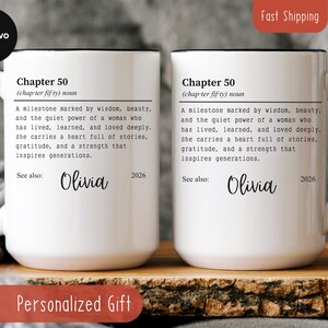 May include: Two white ceramic mugs with black handles and rims. Each mug features the text "Chapter 50" and a definition, along with the name "Olivia" and the year "2026". The mugs are personalized gifts.