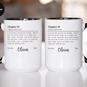 May include: Two white ceramic mugs with black handles and rims. Each mug features the text "Chapter 50" and a definition, along with the name "Olivia" and the year "2026". The mugs are designed for gifting.