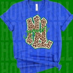 May include: A bright blue short-sleeved t-shirt featuring a large, stylized monogram of the letters NL with a brown and black leopard print pattern. The word jaguars is written in a green cursive script across the center of the monogram.