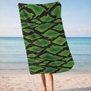 May include: A rectangular beach towel featuring a vibrant green and black snakeskin pattern. The design consists of repeating diamond-shaped scales in varying shades of bright green, separated by dark black lines that create a textured appearance.