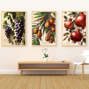 Puede incluir: Tres impresiones botánicas enmarcadas con uvas, dátiles y granadas. La impresión de uvas muestra uvas moradas oscuras con hojas verdes. La impresión de dátiles muestra dátiles marrones con hojas de palma verdes. La impresión de granadas muestra granadas rojas con hojas verdes.