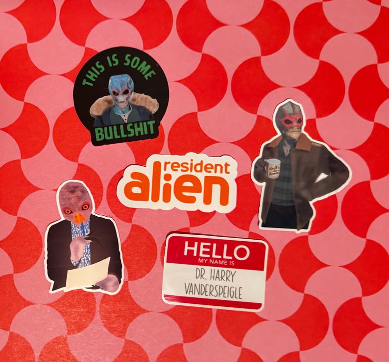 May include: A collection of stickers featuring characters from the show "Resident Alien." The stickers include images of the alien character in various poses, with text such as "This is some bullshit" and "Hello, my name is Dr. Harry Vanderspeigle."