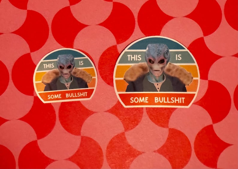 May include: Two stickers featuring an alien with blue skin and a neutral expression. The stickers have the text "THIS IS" above the alien and "SOME BULLSHIT" below. The background is a red and white pattern.