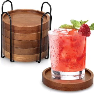 May include: A set of six round wooden coasters in varying shades of brown, stacked in a black metal holder. A glass of red cocktail with ice, a raspberry, and mint sits on one coaster. The coasters are approximately 4 inches in diameter.