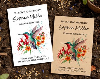 May include: Two memorial seed packets with a hummingbird design. The packets read "IN LOVING MEMORY" and include a name and dates. The hummingbird is depicted with red, blue, and green colors, surrounded by orange flowers. The text "FROM SEED TO BLOOM, MY LOVE IS STILL WITH YOU!" is also included.