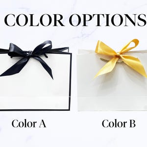 May include: Two white gift bags with black trim and bows. One bag has a black bow, and the other has a gold bow. The text "COLOR OPTIONS" is at the top, with "Color A" and "Color B" below the bags.