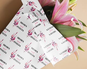 May include: White wrapping paper with a repeating floral design in shades of pink and purple. The text "SHAWN and EVELYN" is printed on the paper. A bouquet of pink lilies is partially visible.