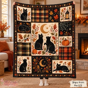 Op de afbeelding: Een rechthoekige plaid met een patchworkontwerp met zwarte katten, herfstbladeren, pompoenen, ruitpatronen, een maansikkel en een lantaarn. De rand is versierd met kleine oranje en gele bloemen op een donkere achtergrond.