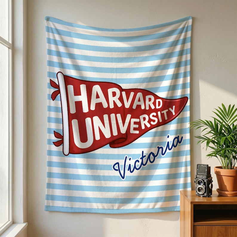 以下が含まれることがあります： 赤い旗に白い文字で「HARVARD UNIVERSITY」と書かれた壁掛け。背景は水色と白のストライプ。旗の下には筆記体で「Victoria」と書かれています。サイズはおよそ150cm x 200cmです。