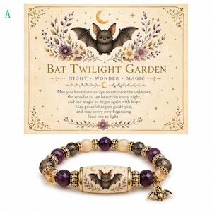 May include: A beaded bracelet featuring a central cylindrical bead with a bat illustration, flanked by purple, gold, and dark faceted beads with gold-tone spacers. A small metal bat charm hangs from the side, accompanied by a decorative card.